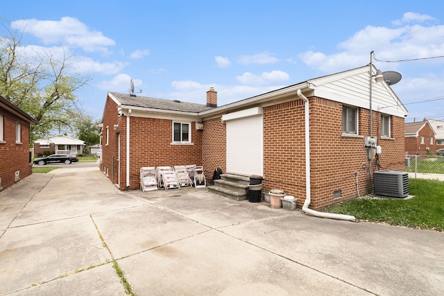 back of house featuring brick siding, crawl space, central AC unit, a chimney, and fence