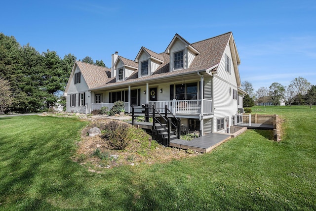 view of front facade featuring a porch, a shingled roof, a front yard, and a chimney