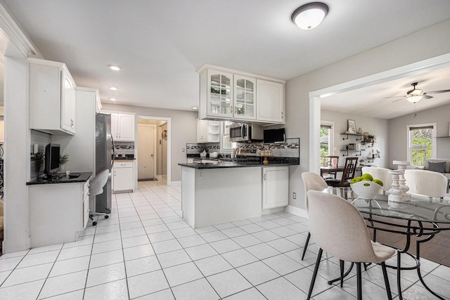kitchen with decorative backsplash, a peninsula, glass insert cabinets, open floor plan, and appliances with stainless steel finishes
