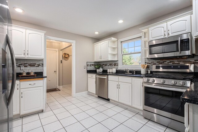 kitchen with white cabinets, tasteful backsplash, dark countertops, and stainless steel appliances