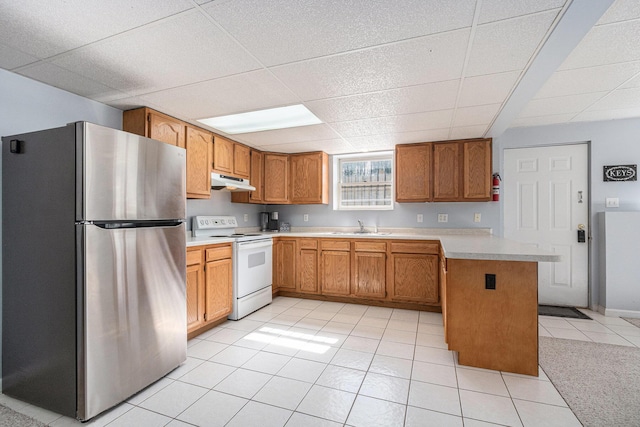 kitchen featuring freestanding refrigerator, a drop ceiling, electric stove, under cabinet range hood, and a sink