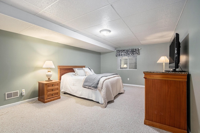 carpeted bedroom featuring baseboards, visible vents, and a drop ceiling