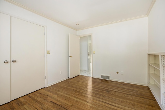 unfurnished bedroom with ornamental molding, wood finished floors, and visible vents