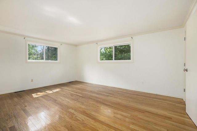 unfurnished room featuring crown molding, a healthy amount of sunlight, and light wood-style floors