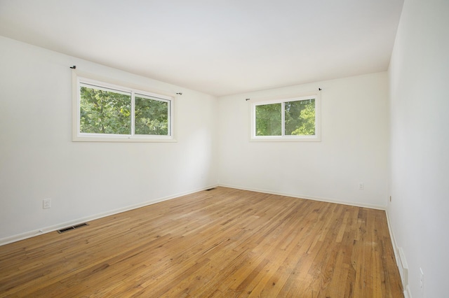 empty room featuring baseboards, visible vents, and hardwood / wood-style flooring