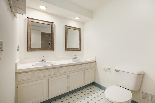 full bath with a sink, toilet, double vanity, and visible vents