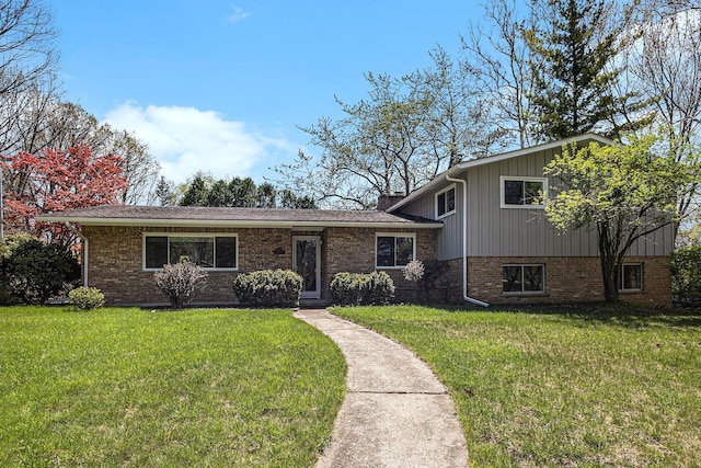 split level home with a chimney, a front lawn, and brick siding