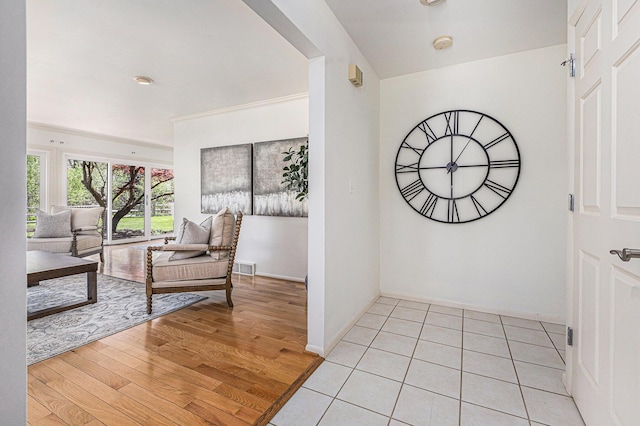 foyer entrance with baseboards, light wood finished floors, and visible vents