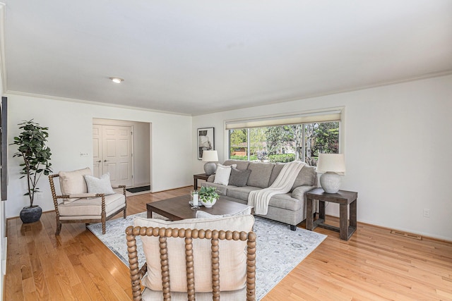 living area with visible vents, ornamental molding, and light wood finished floors
