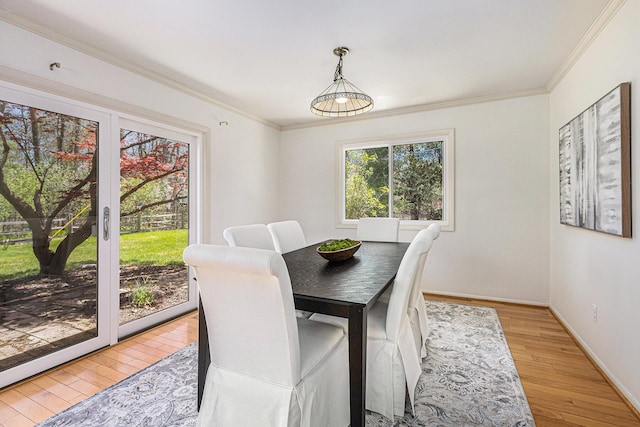 dining room with light wood-type flooring, ornamental molding, and baseboards