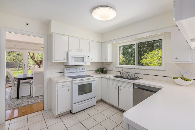 kitchen with a sink, white appliances, light countertops, white cabinetry, and light tile patterned floors