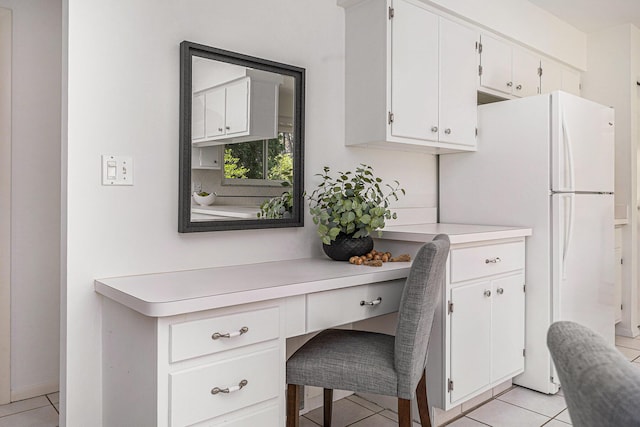 interior space with light countertops, light tile patterned floors, white cabinets, and built in desk