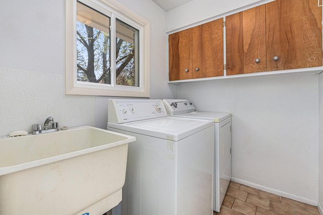 laundry area featuring baseboards, a sink, cabinet space, and independent washer and dryer