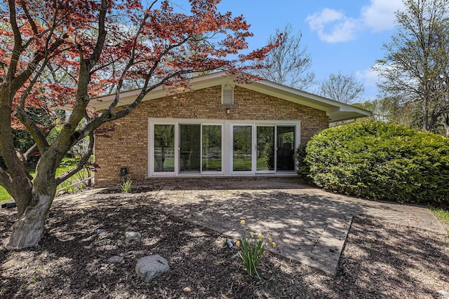 rear view of property with a patio and brick siding