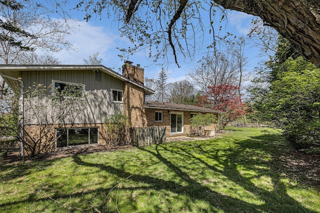 rear view of property featuring board and batten siding, a lawn, a chimney, and brick siding
