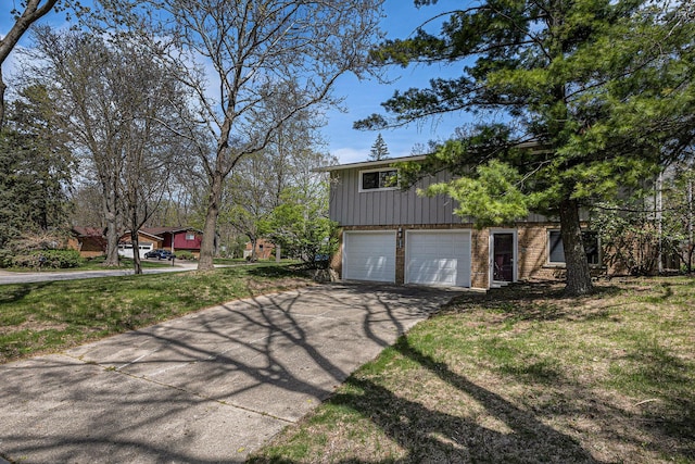 view of side of property with brick siding, a garage, board and batten siding, a lawn, and driveway