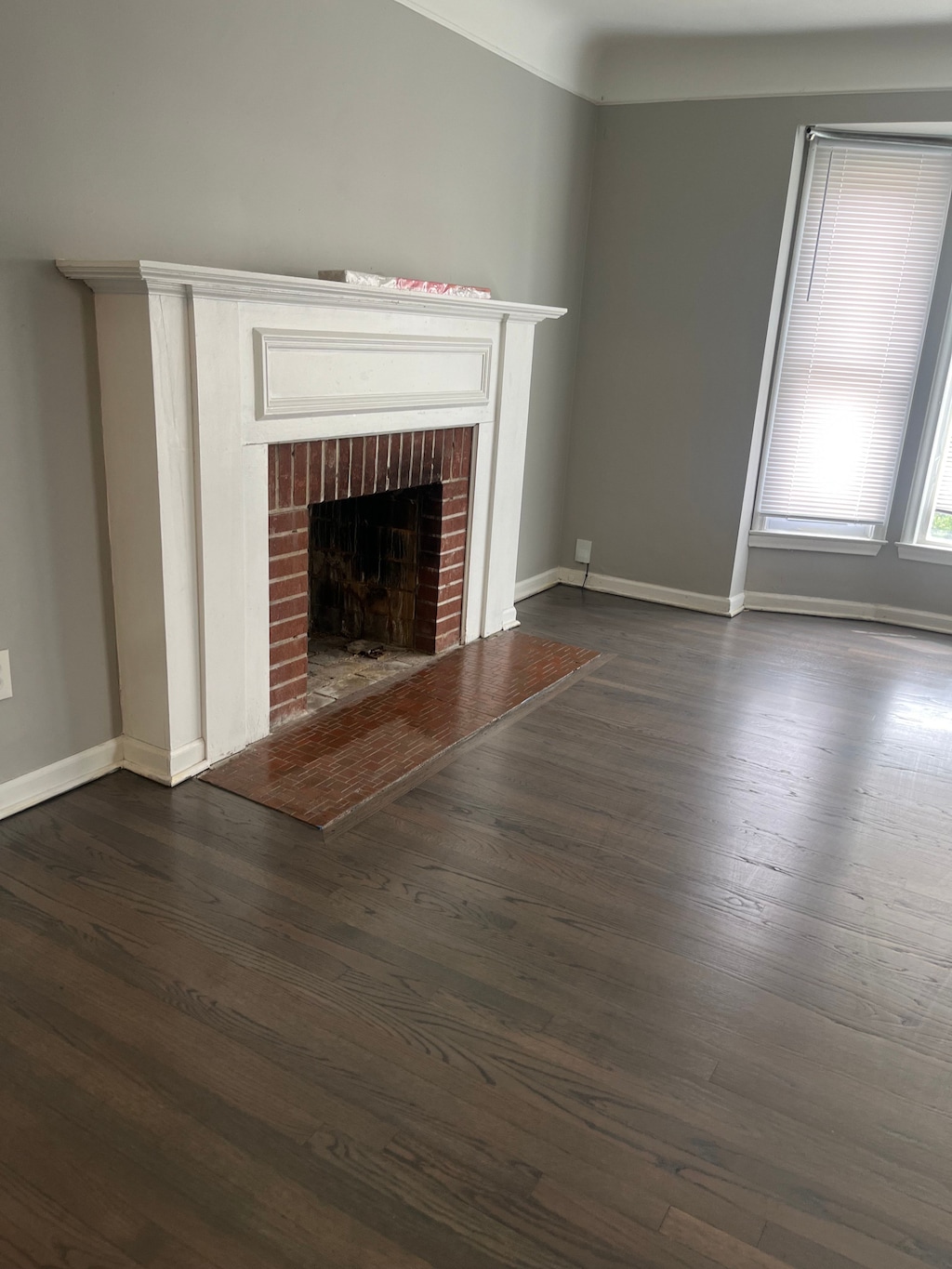 unfurnished living room featuring baseboards, dark wood-style flooring, and a fireplace