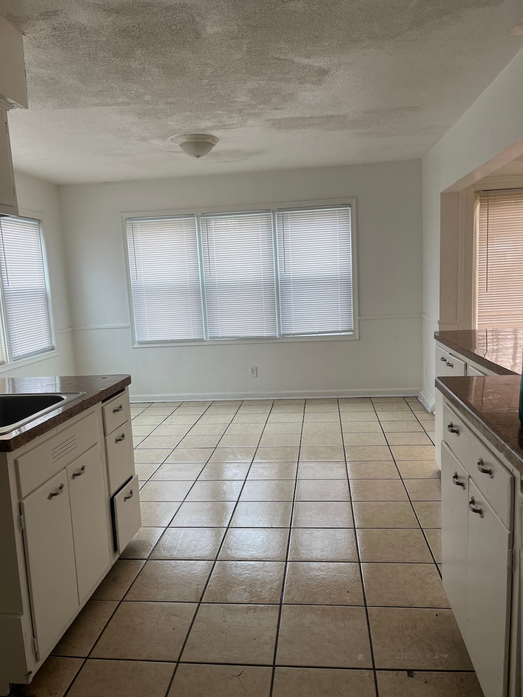 unfurnished dining area featuring light tile patterned floors, a textured ceiling, and a healthy amount of sunlight