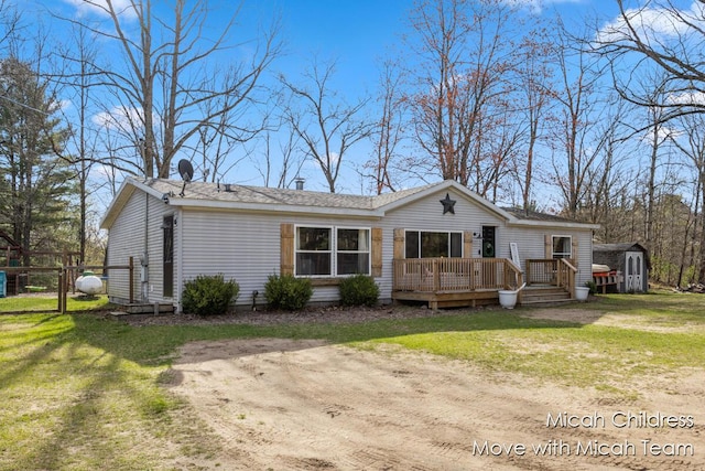 rear view of house with a storage shed, a wooden deck, an outdoor structure, and a yard
