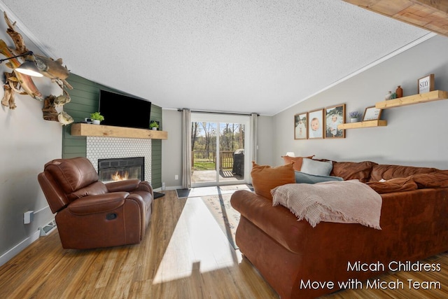 living area featuring a textured ceiling, a tiled fireplace, and wood finished floors