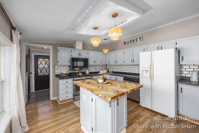 kitchen featuring appliances with stainless steel finishes, decorative backsplash, butcher block countertops, and wood finished floors