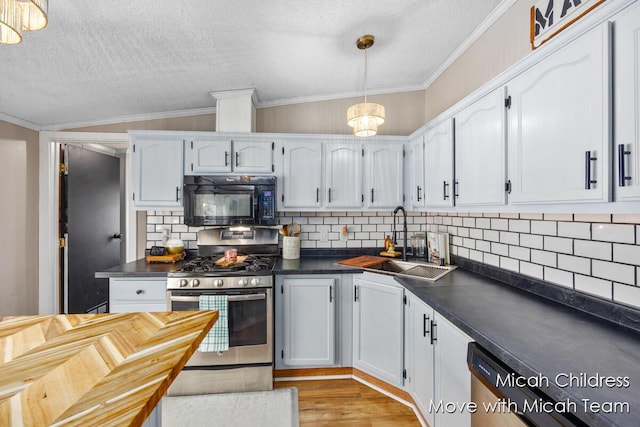 kitchen with black microwave, stainless steel range with gas stovetop, crown molding, dark countertops, and a sink