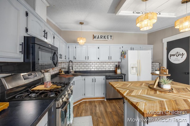 kitchen with wooden counters, dark wood-style floors, tasteful backsplash, a sink, and appliances with stainless steel finishes