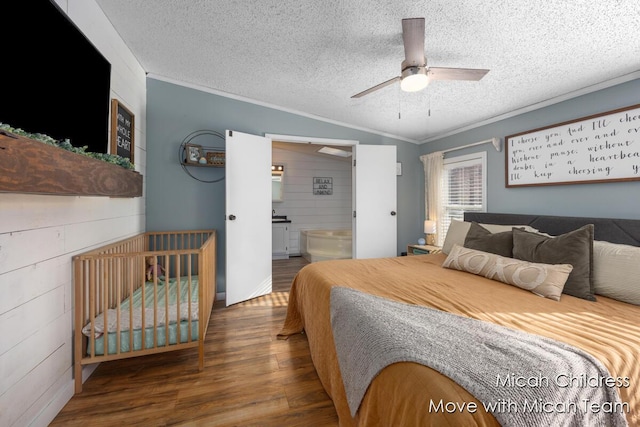 bedroom featuring a textured ceiling, crown molding, wood finished floors, lofted ceiling, and ensuite bathroom