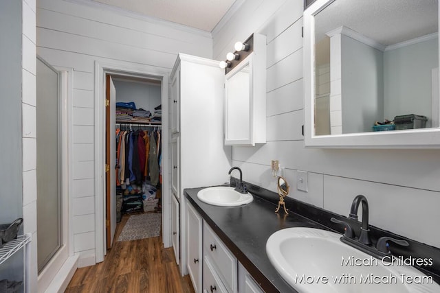 full bathroom featuring a sink, ornamental molding, a shower stall, and a spacious closet