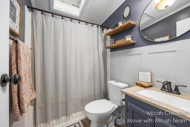 bathroom with wainscoting, a decorative wall, toilet, a textured ceiling, and a shower with curtain