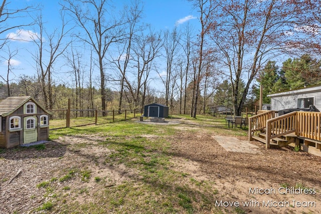 view of yard with an outdoor structure, fence, a wooden deck, and a shed