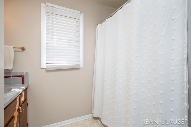 bathroom with baseboards, tile patterned floors, and vanity