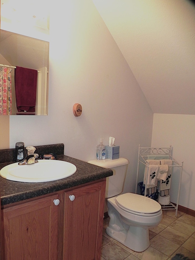 bathroom featuring vanity, tile patterned flooring, toilet, and lofted ceiling