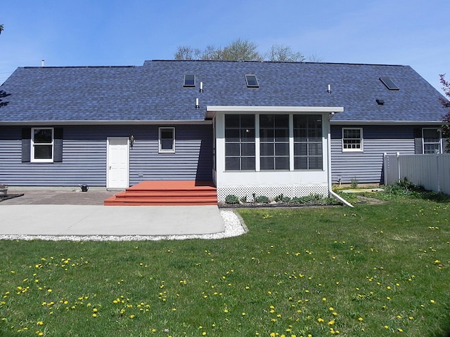 rear view of house with a lawn, roof with shingles, a sunroom, and a patio