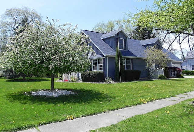 view of front of home featuring a shingled roof and a front yard