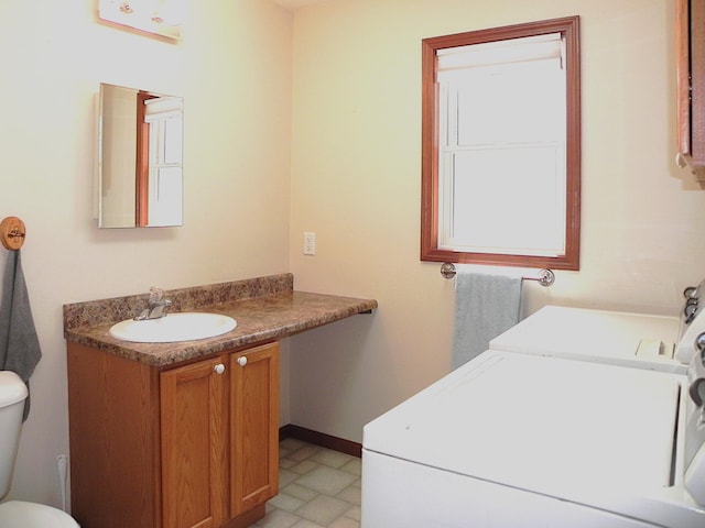 half bath featuring toilet, washing machine and dryer, and vanity