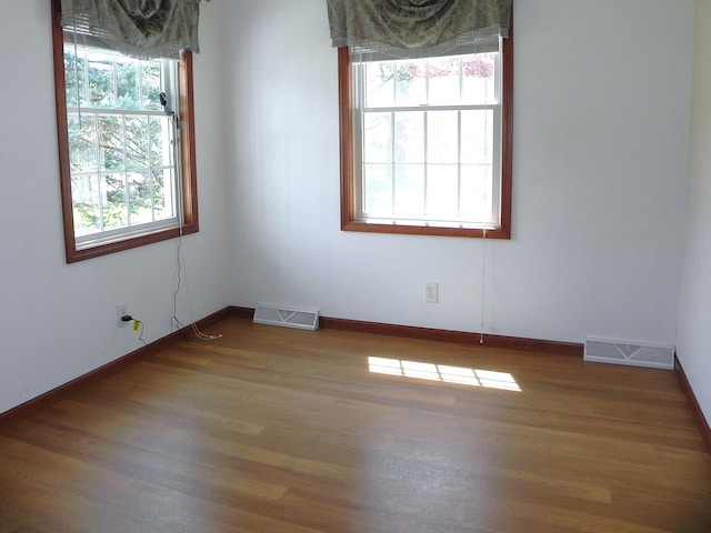 spare room with visible vents, baseboards, and wood finished floors