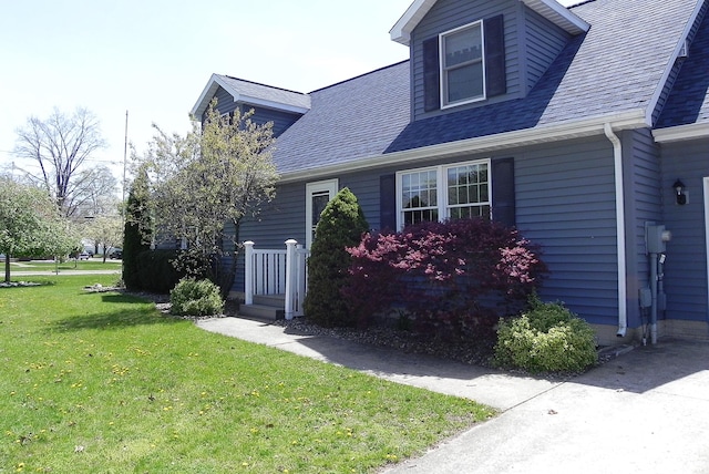 view of property exterior with a lawn and a shingled roof