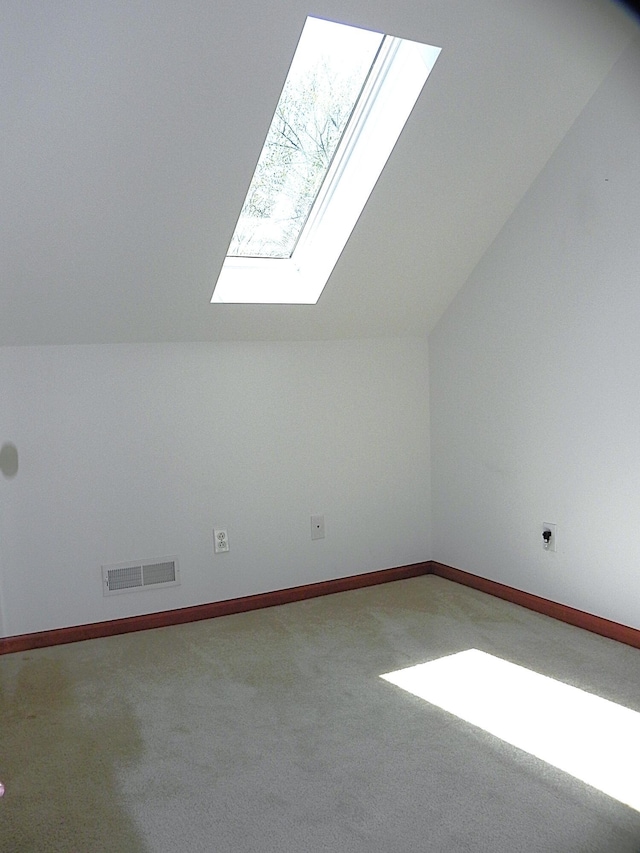 additional living space featuring visible vents, baseboards, carpet floors, and vaulted ceiling with skylight