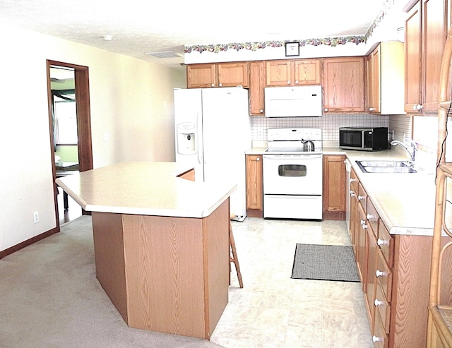 kitchen with brown cabinets, a sink, white appliances, light countertops, and tasteful backsplash