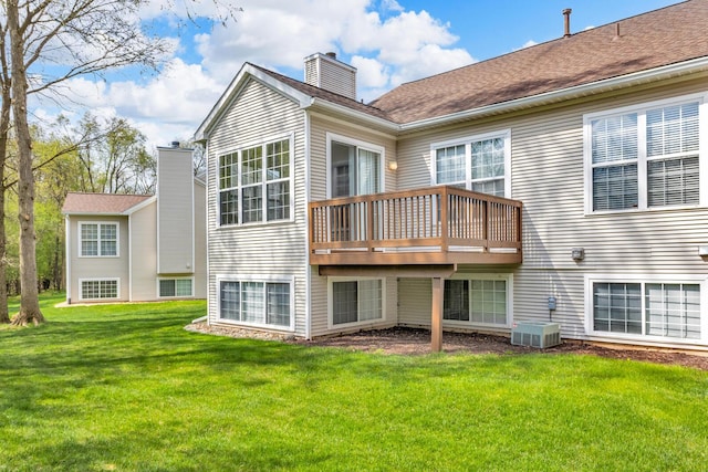 rear view of property featuring a lawn, a wooden deck, central air condition unit, and a chimney