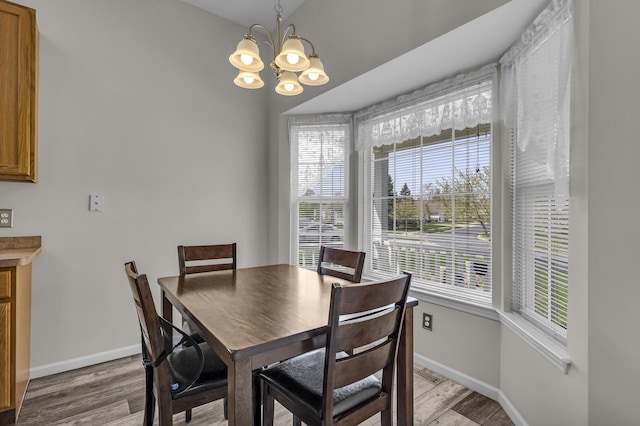 dining space with light wood-style floors, baseboards, and a chandelier