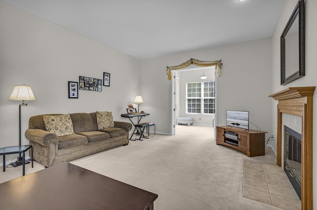 living room featuring a glass covered fireplace, baseboards, and light colored carpet