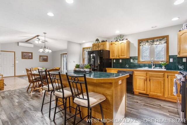 3087 38th St, Hamilton, MI 49419 - kitchen with a sink, light wood-style floors, an AC wall unit, a kitchen bar, and black appliances