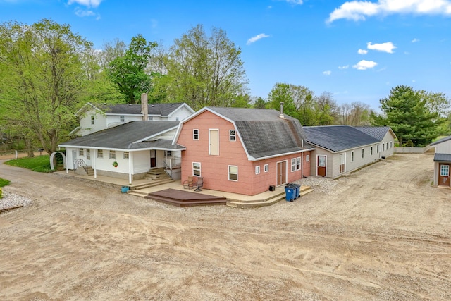 back of property featuring a wooden deck, roof with shingles, and a gambrel roof