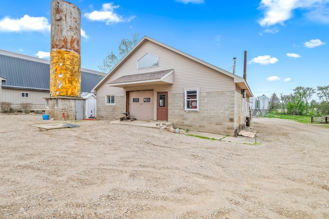 bungalow-style house featuring an outdoor structure, concrete block siding, a storage shed, and metal roof