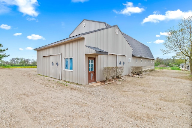 exterior space featuring board and batten siding, driveway, and metal roof