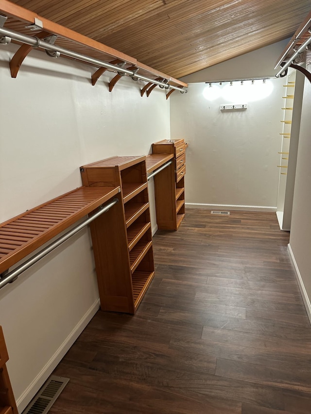 walk in closet featuring visible vents, dark wood-type flooring, and lofted ceiling