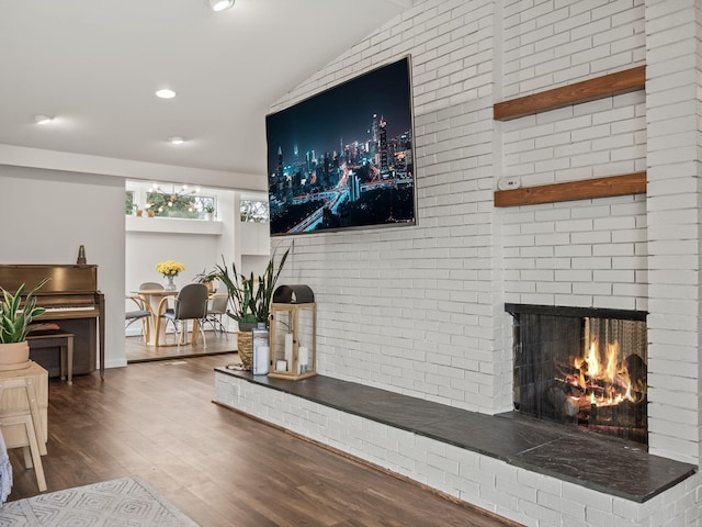 living room with recessed lighting, wood finished floors, lofted ceiling, and a fireplace