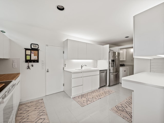 kitchen with independent washer and dryer, a sink, light countertops, stainless steel appliances, and recessed lighting